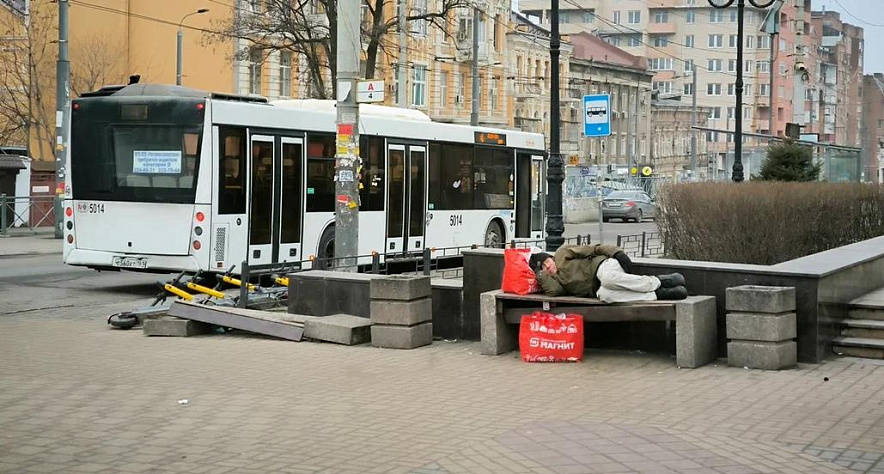 Фото: человек спит на лавке рядом с остановкой в Ростове, кадр 1rnd